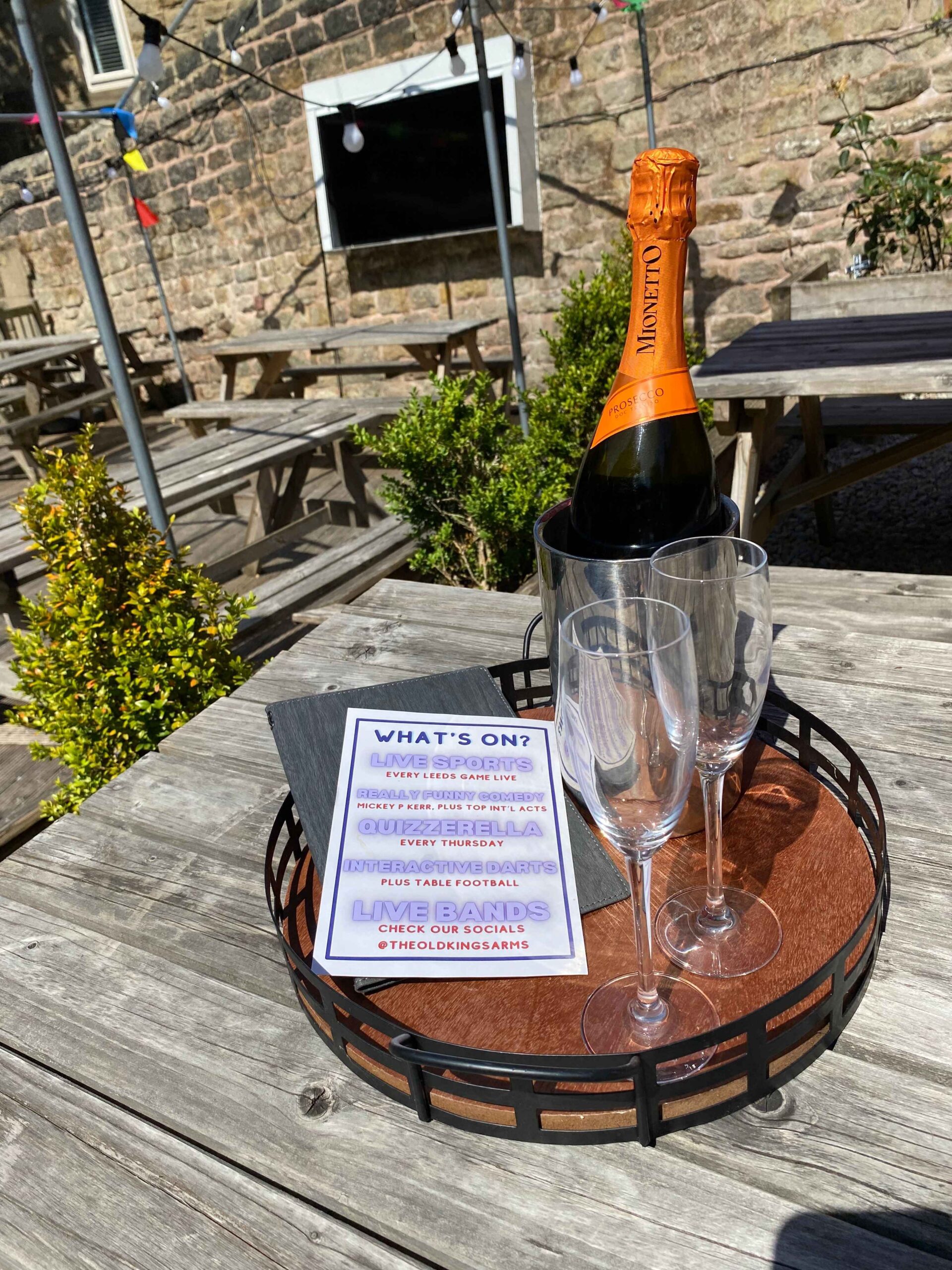 Guests with drinks watching the outdoor screen in the beer garden